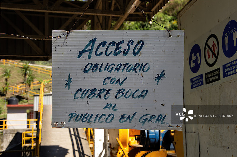 悬挂在工作场所入口处的西班牙语covid-19健康和安全标志图片素材
