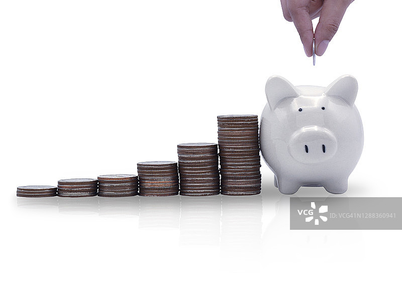 将硬币放入储蓄罐并堆叠硬币以实现增长的手，储蓄、商业、金融和退休概念，白色背景图片素材