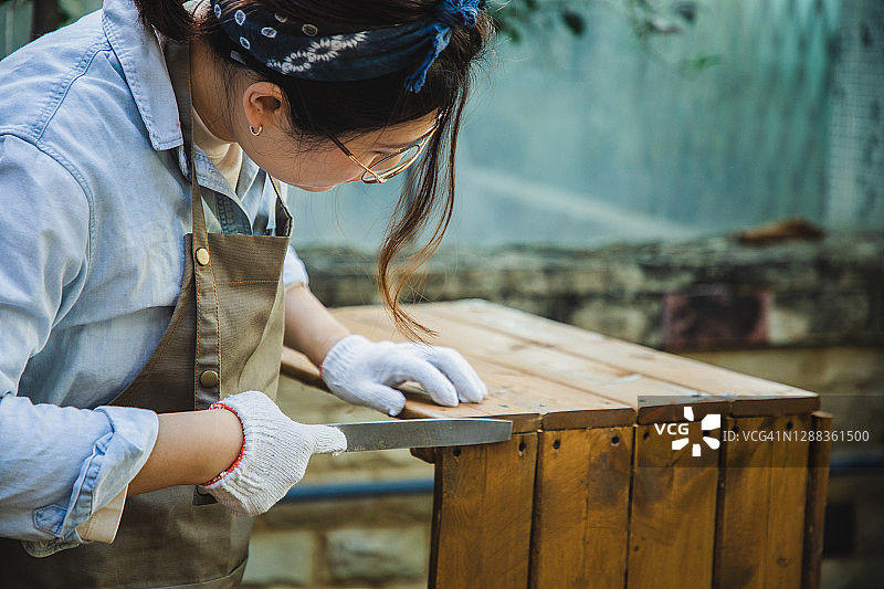亚洲女人用粗锉刀塑造木材图片素材