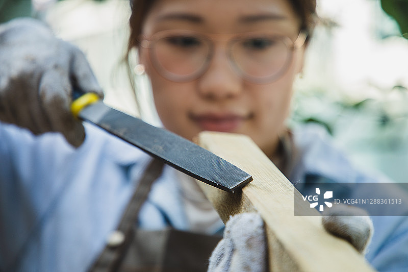 亚洲女人用粗锉刀塑造木材图片素材