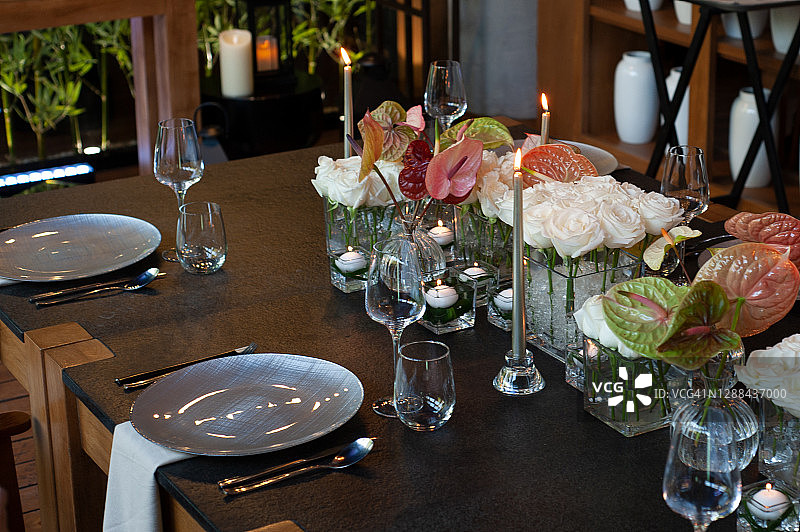 黑色桌子上摆放着蜡烛和鲜花的餐桌图片素材