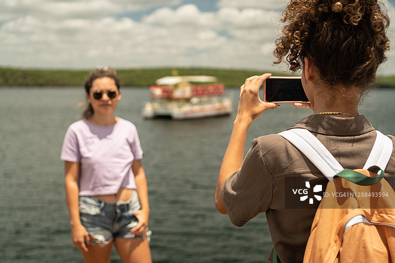 在河边用智能手机拍照图片素材