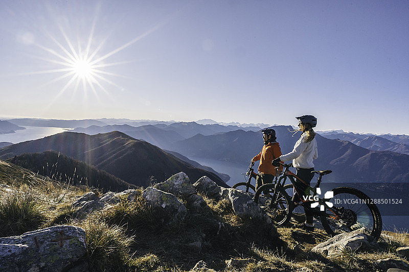 山地自行车骑行者在日出时分山顶小憩图片素材