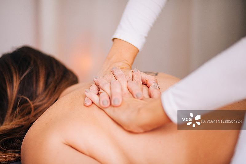 年轻女子在水疗中心享受颈部按摩图片素材