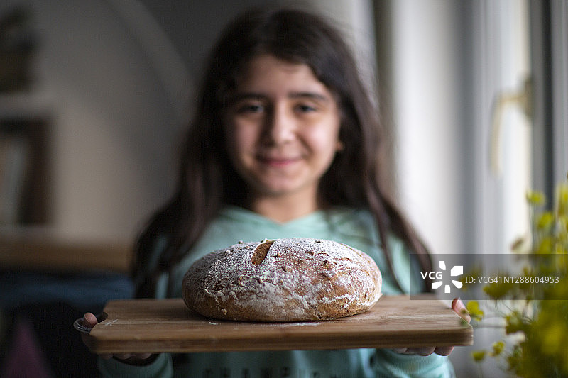 小女孩拿着自制的酵母酸面包图片素材