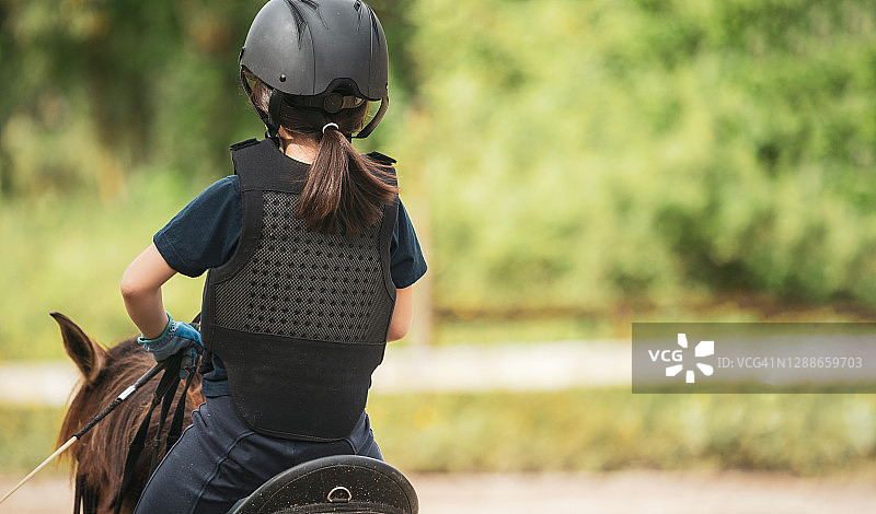 年轻女孩戴着头盔骑马图片素材