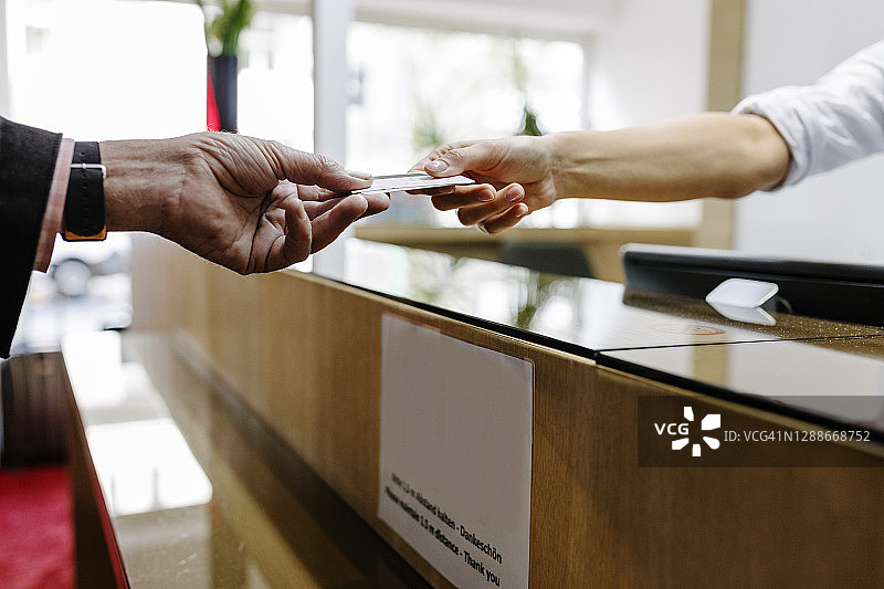 顾客隔空向接待员递信用卡图片素材