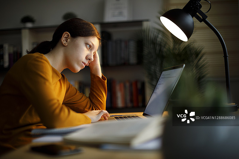 担忧的青少年女孩在家学习到深夜图片素材