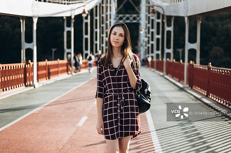 穿着格子连衣裙，背着包的美丽年轻女人图片素材