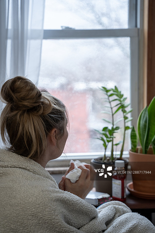 年轻女子生病在家，望着雨天窗外图片素材
