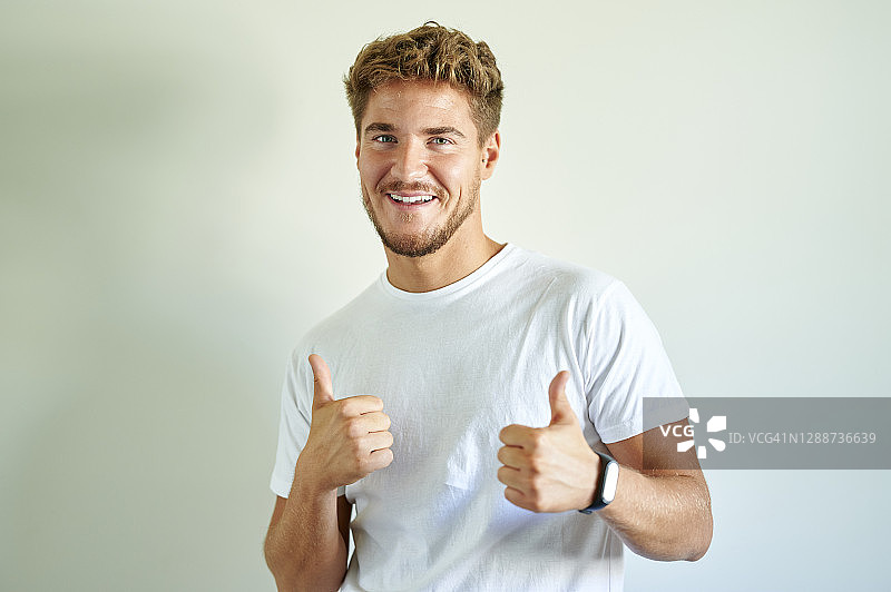 男子在白墙前做出胜利姿态图片素材