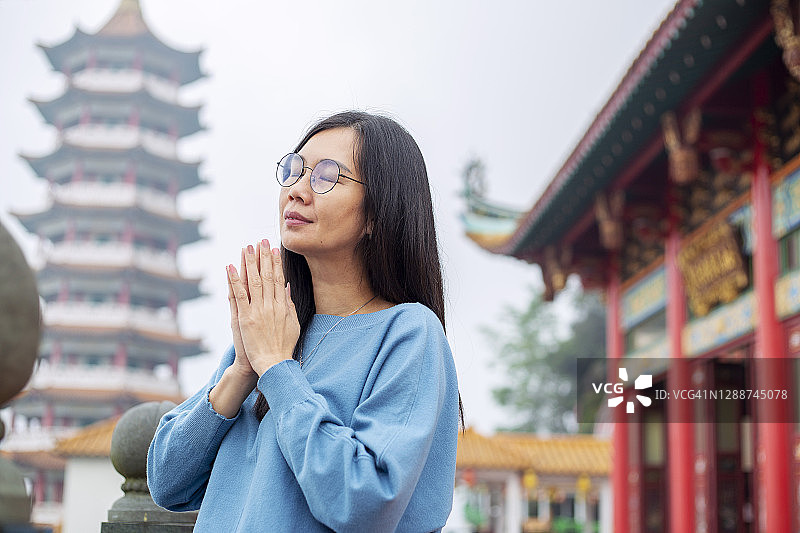 在寺庙外祈祷的亚洲妇女图片素材