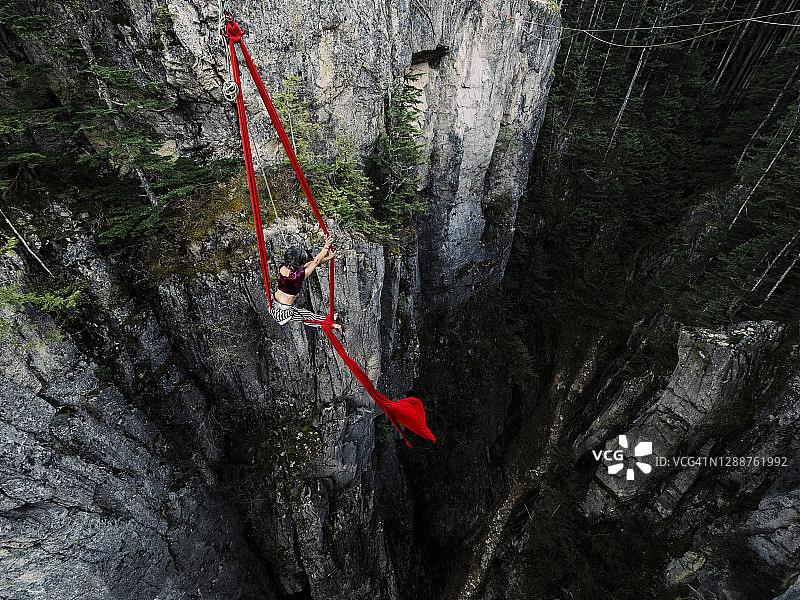 一位女杂技演员在红色空中绸带上表演图片素材