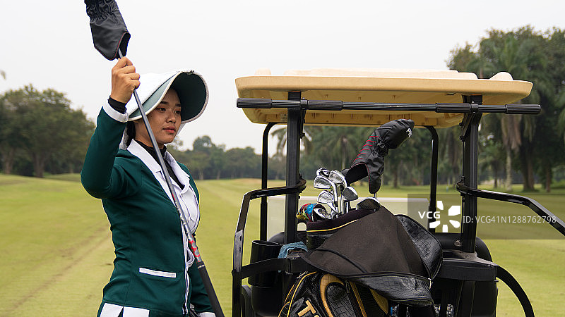 身穿绿色西装和高尔夫球车的高尔夫球童。图片素材