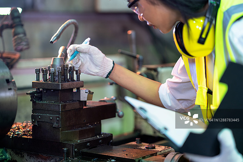 女工程师在制造工厂工作前检查机械零件图片素材
