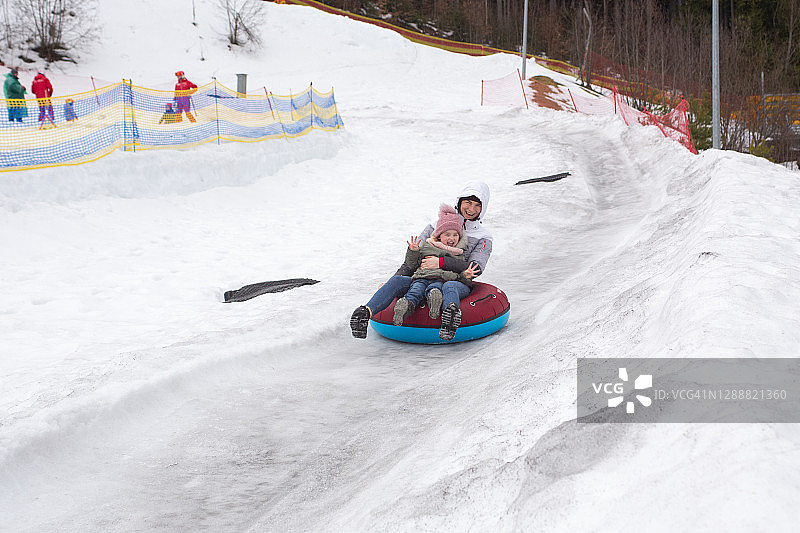 母女坐在充气圈上滑滑梯图片素材