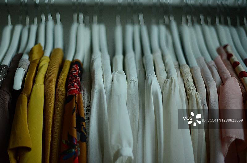 按颜色排列的一排衣架上不同颜色的女式衬衫图片素材