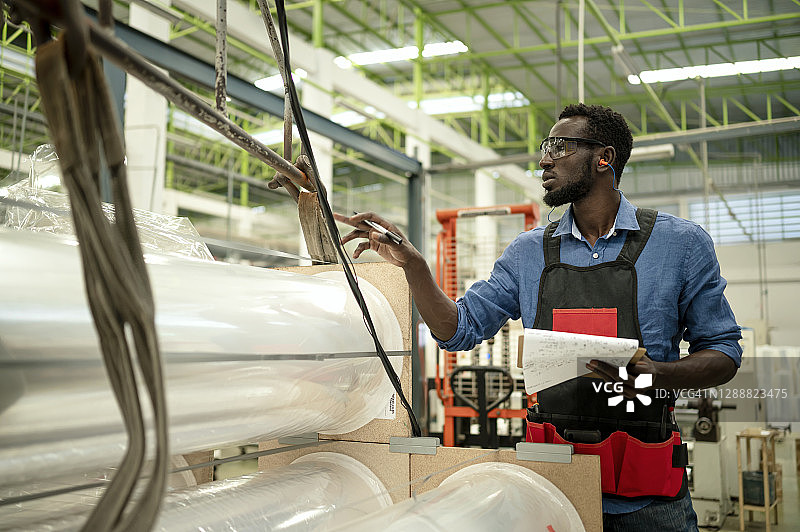 质检工程师在工厂生产线上检查塑料卷原材料图片素材