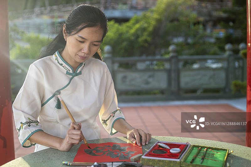 亚洲女人在后院花园里写中国书法图片素材