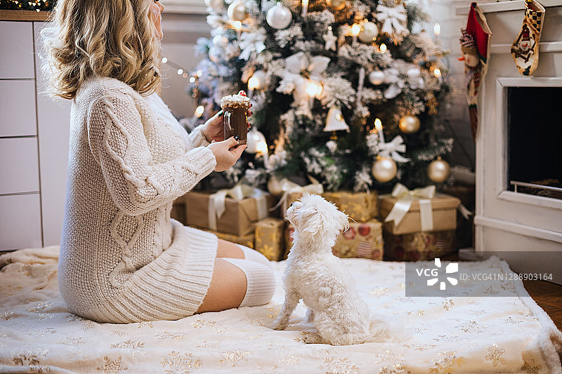 年轻女子在温馨的圣诞氛围中喝热巧克力图片素材