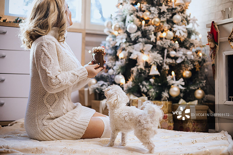 年轻女子在温馨的圣诞氛围中喝热巧克力图片素材