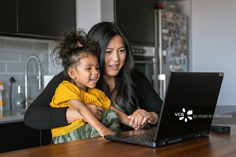 母亲帮助小学生女儿进行线上学习视频会议图片素材