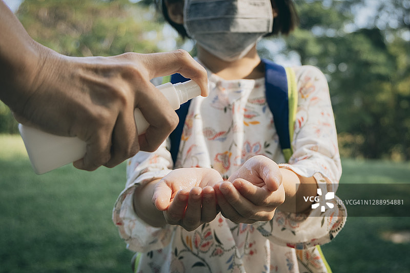 在户外，妈妈把洗手液挤到小女儿手里图片素材