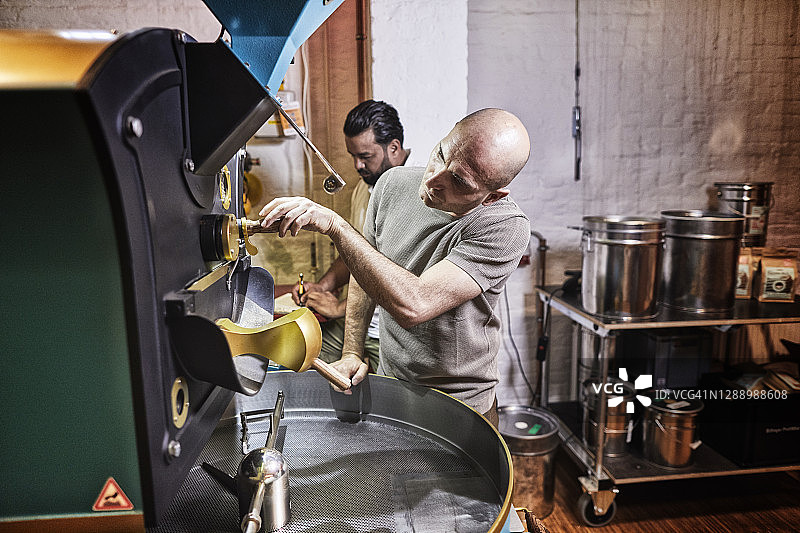 在咖啡烘焙厂的机器旁工作的男人图片素材