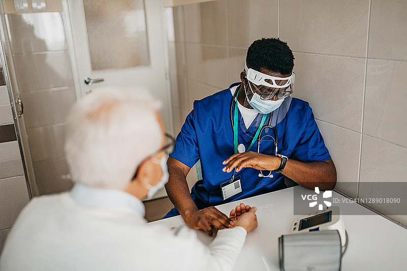 年轻医生在家中为病人检查脉搏和血压图片素材