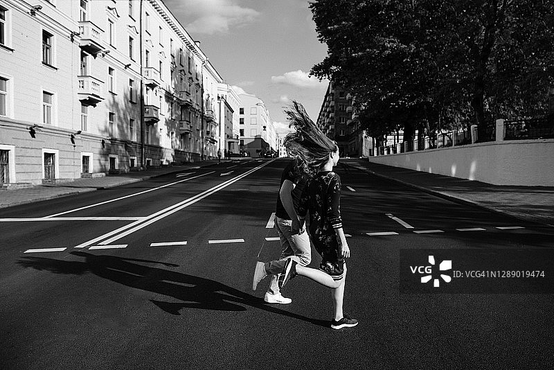 年轻情侣手牵手城市街道跑步图片素材
