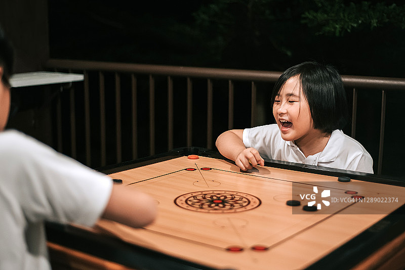 两个在别墅里玩卡罗姆棋的亚洲兄妹图片素材