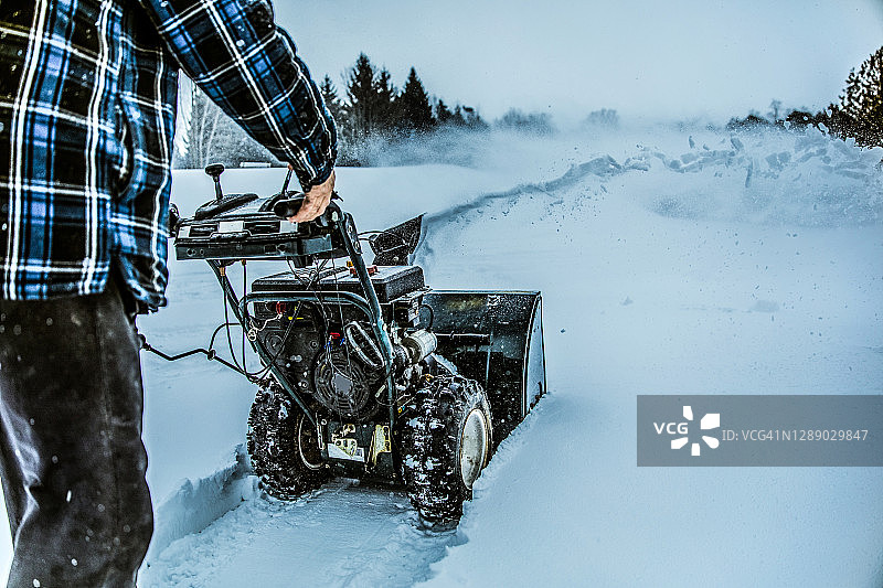 雪天冬日——男子在户外使用扬雪机图片素材