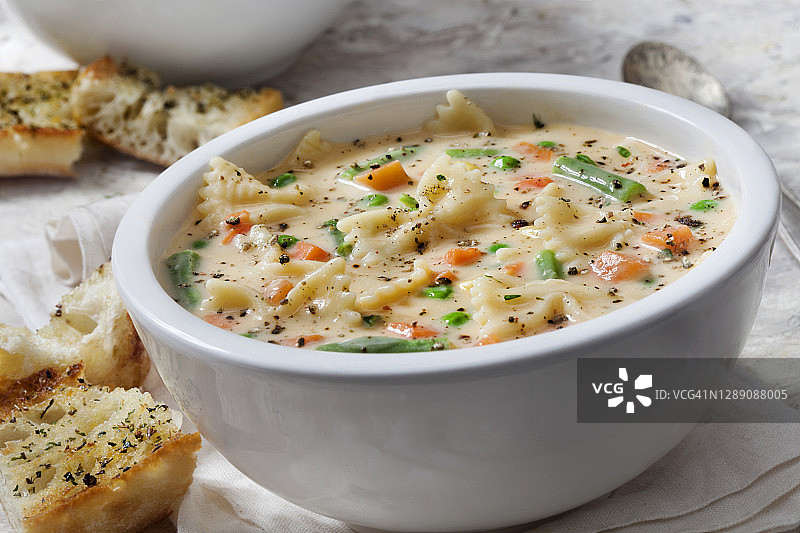 奶油通心粉芝士汤配蝴蝶结面、混合蔬菜和大蒜面包图片素材