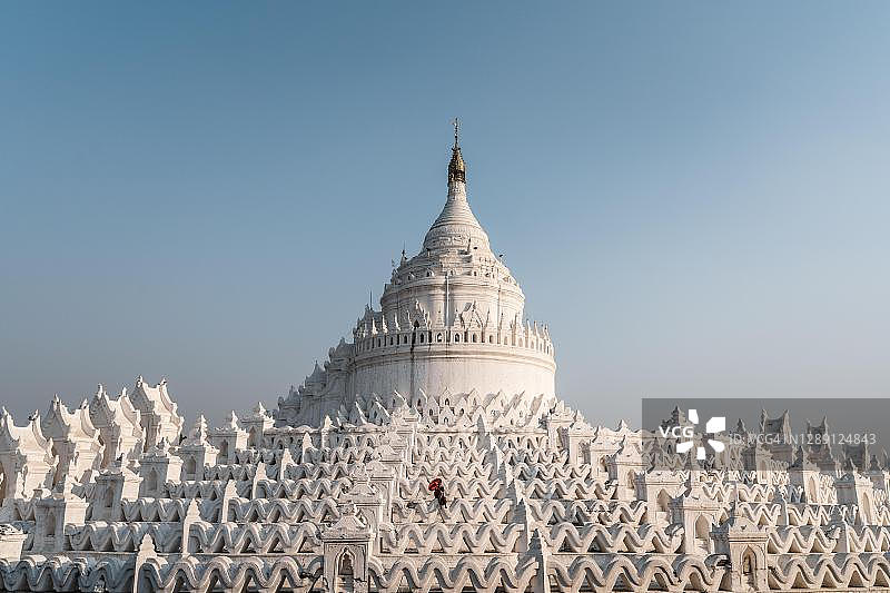 缅甸敏贡辛比梅佛塔前持红伞的佛教僧侣图片素材