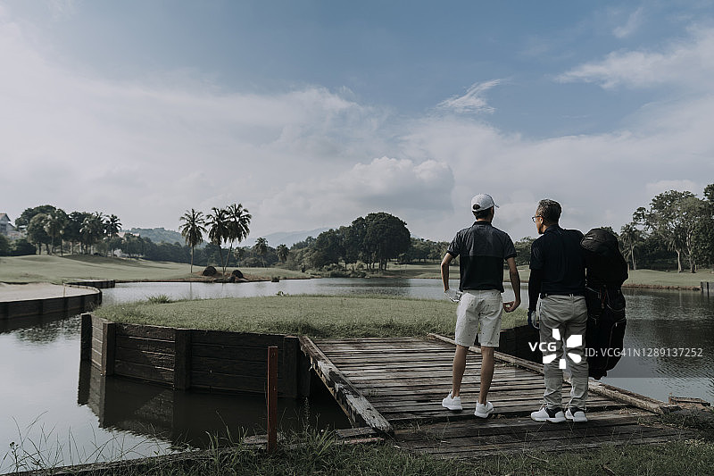 亚裔父子高尔夫球手欣赏高尔夫球场景色图片素材