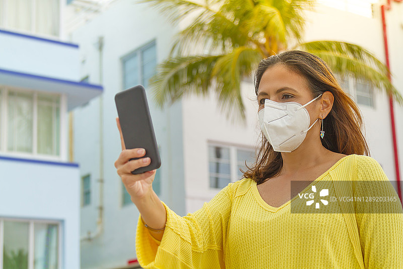 年轻的拉丁裔女人在美国佛罗里达州迈阿密海滩的海洋大道上用手机拍照图片素材