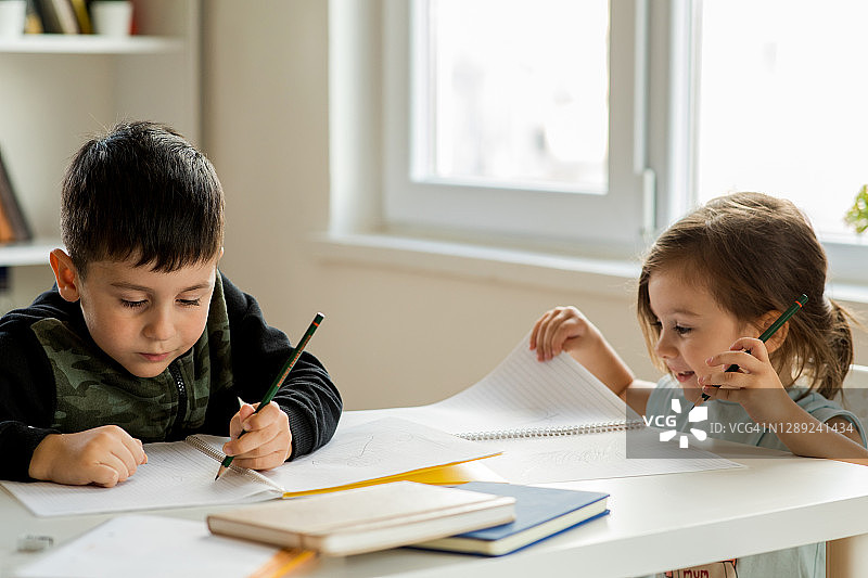 两名年轻的兄弟姐妹在家写东西图片素材