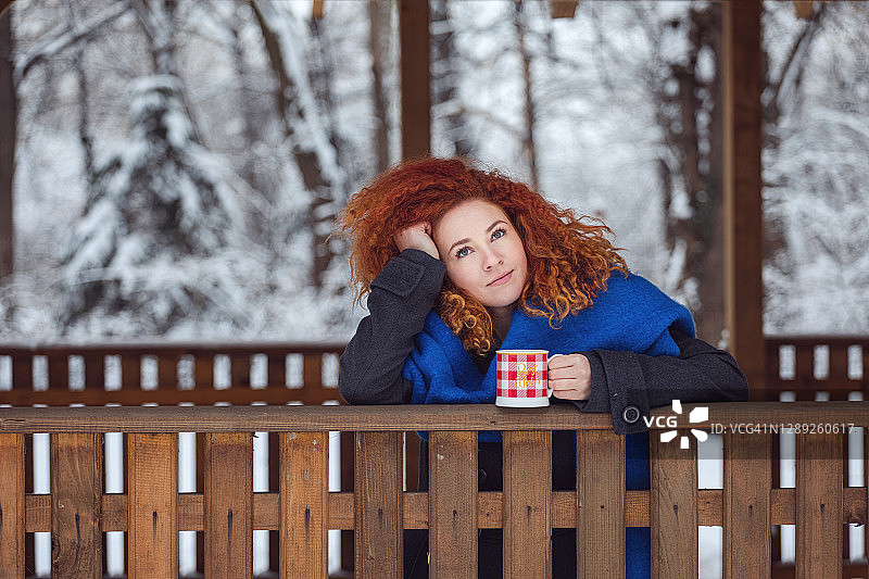 在冬季森林户外享受热茶或咖啡的年轻漂亮女子图片素材