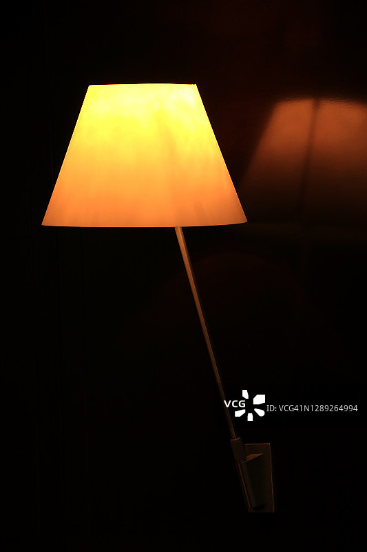 黑色背景上的帝国灯罩壁灯及其在墙上的倒影图片素材