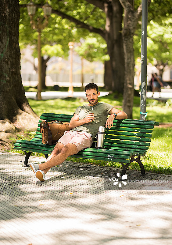 夏天在公园长椅上喝马黛茶的年轻人图片素材
