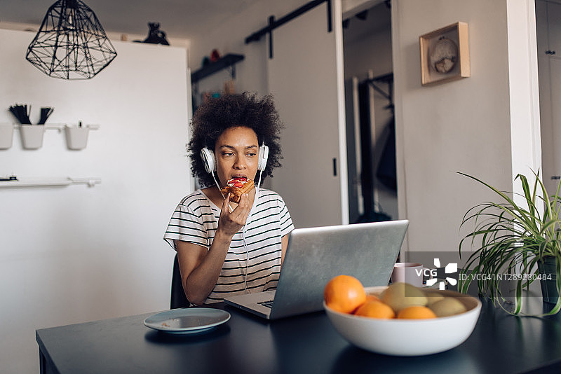 年轻的非裔女性在家享用早餐并线上工作图片素材