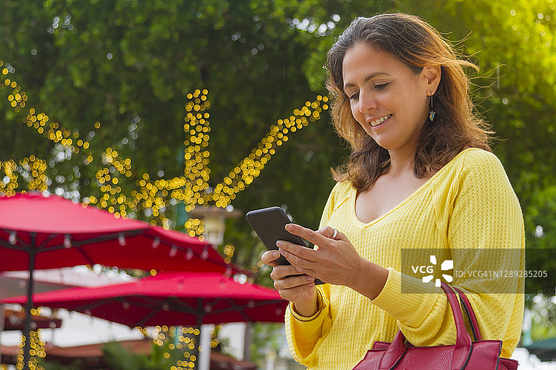 在美国佛罗里达州迈阿密海滩使用智能手机的微笑年轻女人图片素材