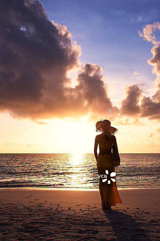 在热带海滩享受日落的年轻女人图片素材