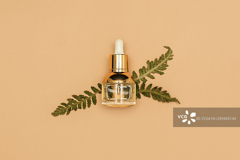 米色背景上的精油化妆品瓶和白色护手霜罐，带有绿色草本叶子，天然美容产品概念，极简扁平风格构图，顶视图图片素材