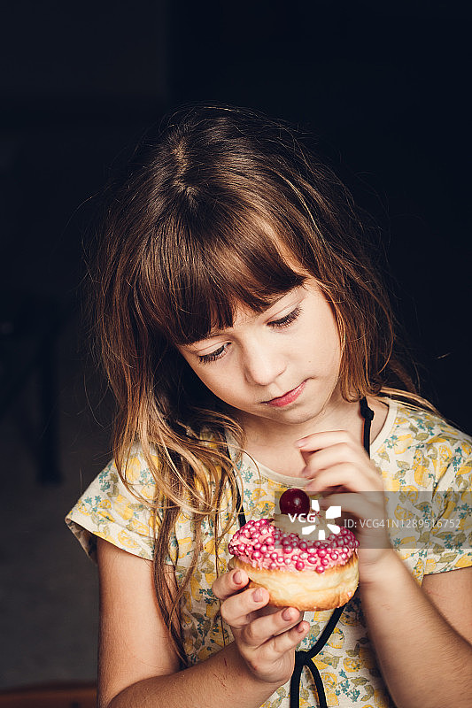 吃粉色果酱甜甜圈的小女孩图片素材