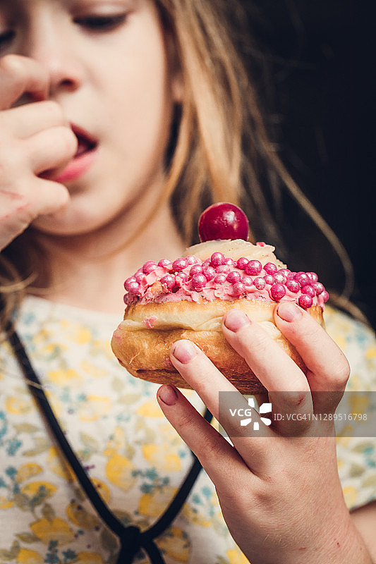吃粉色果酱甜甜圈的小女孩图片素材