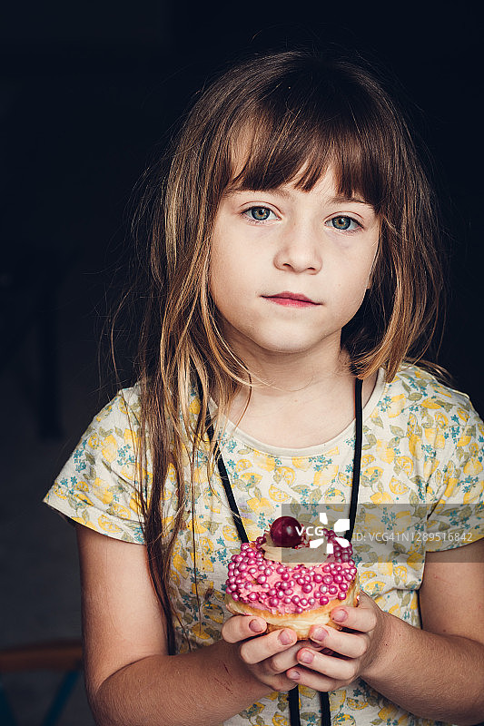 吃粉色果酱甜甜圈的小女孩图片素材