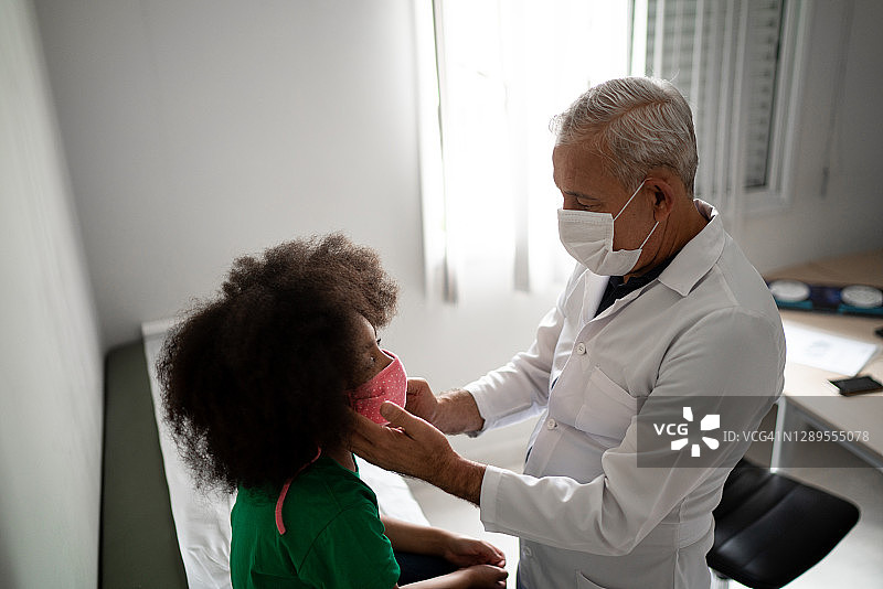 医生就诊期间检查女孩 - 使用口罩图片素材
