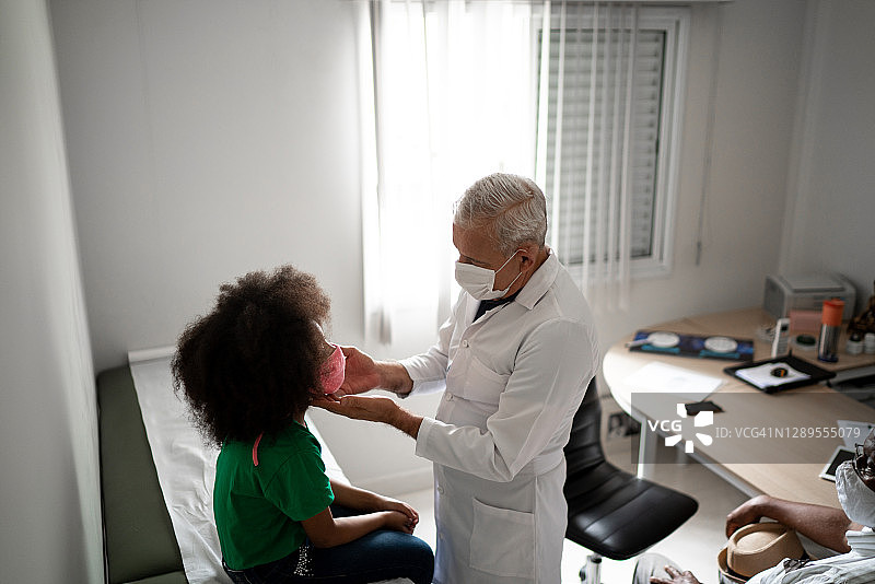 医生就诊期间检查女孩 - 使用口罩图片素材