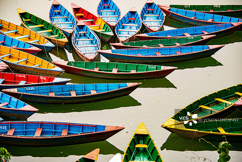 尼泊尔博克拉费瓦湖上漂浮的彩色独木舟图片素材